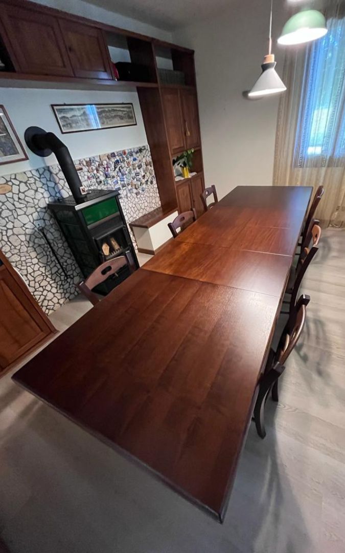 Tavolo fratino allungabile in legno color noce scuro in una sala da pranzo in stile arte povera.